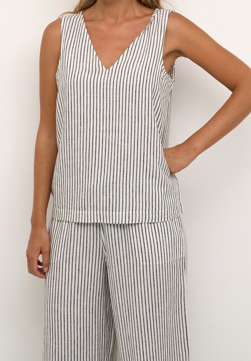 Haut sans manches rayé en blanc et bleu marine, présentant un décolleté en V et une coupe décontractée. Fabriqué en tissu léger avec une texture lisse.