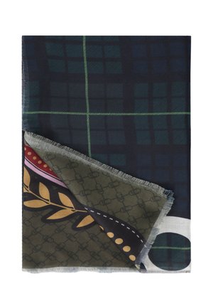 Tela doblada que muestra un patrón cuadriculado de color verde oscuro y azul marino con una esquina doblada que revela un diseño multicolor que incluye hojas de olivo y puntos.