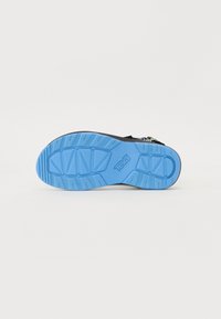 Svart sandal med en teksturert overdel og en blå gummisåle med et distinkt mønster og "Teva"-logo. Justerbare stroppdetaljer.