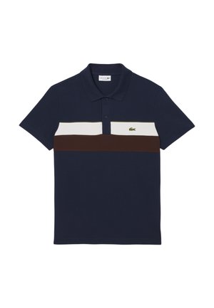 Polo bleu marine avec une rayure horizontale blanche et marron, patte de boutonnage à deux boutons et logo brodé vert sur la poitrine gauche. Matière en coton.