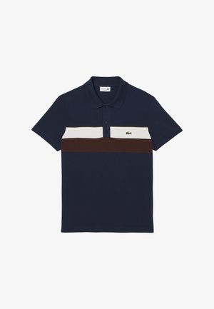 Polo blu navy con una striscia orizzontale bianca e marrone, colletto con due bottoni e logo ricamato verde sul lato sinistro del petto. Materiale in cotone.