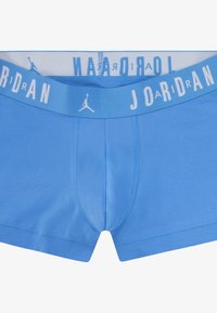 Blå bomulds-boxershorts med en bred hvid linning, der har teksten "JORDAN" og et logo. Designet er sømløst med en frontlomme.