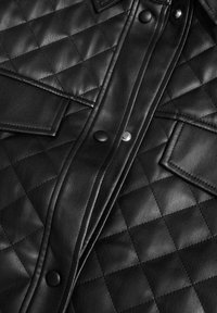 Czarna skórzana kurtka pikowana, z zapięciem na guziki, dwiema kieszeniami na piersi oraz widocznymi detalami przeszycia na teksturowanej powierzchni.