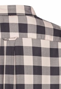 Gros plan d'un tissu de chemise à carreaux noir et blanc montrant le col et les détails du haut du dos.