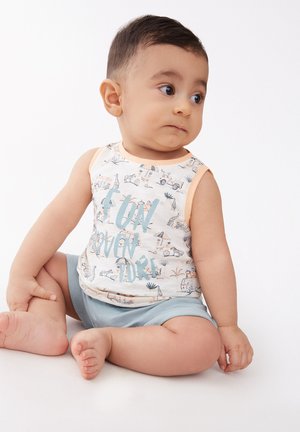 Camiseta de algodón sin mangas con un fondo beige claro, que presenta un estampado de animales divertido y el texto azul "DIVERTIDA AVENTURA". Pantalones cortos azul claro.