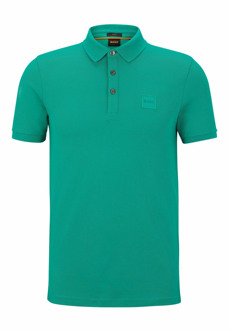 Polo vert à manches courtes avec trois boutons foncés, un col et un petit écusson logo embossé sur la poitrine gauche.