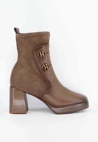 Stivale alla caviglia marrone caratterizzato da una combinazione di pelle liscia e camoscio, due bottoni dorati circolari e un tacco impilato con una trama a righe verticali.