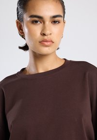 Braunes Baumwoll-T-Shirt mit Rundhalsausschnitt und kurzen Ärmeln, im lässigen Schnitt und mit glatter Textur, geeignet für Freizeitkleidung.