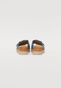 Blue fabric slip-on shoes with a woven design, cork accent midsole, and rubber outsole, featuring a rounded back and open sides.