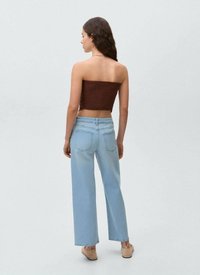 Brauner Smocked-Crop-Top kombiniert mit hellblauen, hochgeschnittenen weit geschnittenen Jeans, die über Gesäßtaschen und einen lässigen Schnitt verfügen.