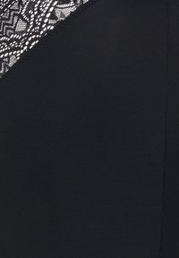 Black fabric with a smooth texture, featuring a section of intricate black lace pattern along the edge. Seam stitching is visible.