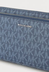 Modra tkaninska denarnica z teksturiranim vzorcem, opremljena z zadrgo in srebrnim napisom "MICHAEL KORS".