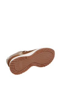 Sneaker marrone con suola in gomma texturizzata e intersuola bianca, vista dalla parte inferiore, che mostra il nome del marchio 'Hackett' sulla suola.