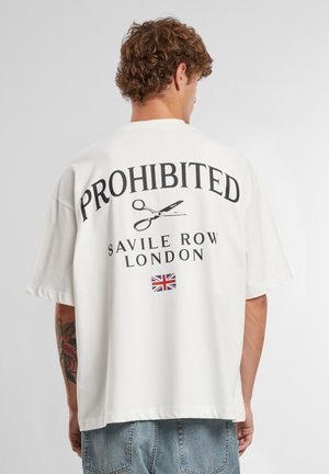 Hvid oversized t-shirt med en sort tryk, der læser "FORBUDT" med saks grafik, "SAVILE ROW LONDON," og et lille britisk flag.