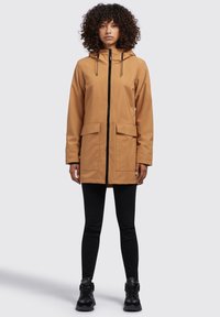 Giacca con cappuccio color khaki con zip frontale, due grandi tasche frontali e dettagli neri. Il materiale sembra leggero e strutturato.