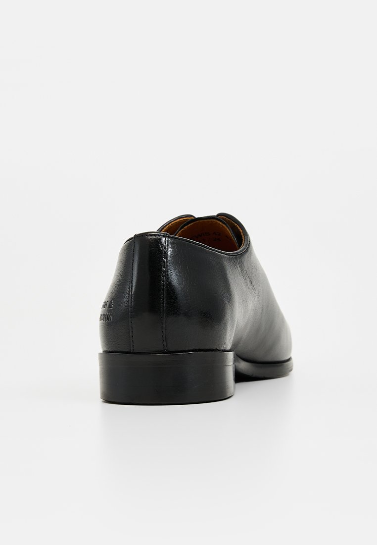 Chaussure habillée en cuir noir avec une texture lisse, bout rond et un petit talon. Logo imprimé sur le talon. Design minimaliste.