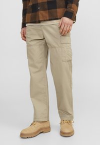 Beige cargo bukser med flere sidelommer, lavet af letvægtsstof. Afsluttet med lige snit og rene sømme, parret med brune støvler.
