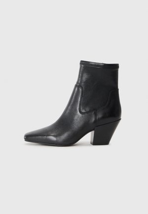 Black leather ankle boot with a pointed toe and a textured upper. Features a geometric block heel and elasticized collar for easy wear.