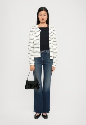 Cardigan a righe bianche in maglia con apertura frontale, top blu navy, jeans in denim blu svasati, borsa nera in vernice e scarpe flat nere.