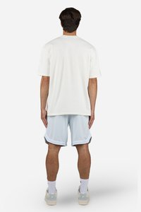 T-shirt blanc à manches courtes associé à un short de sport bleu clair. Le T-shirt présente une coupe droite ; le short a un léger éclat et des bordures contrastantes.