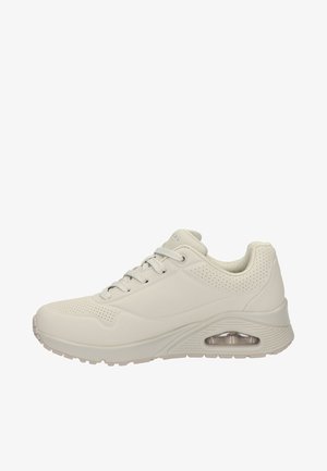 Jasno beżowe sneakersy z gładką syntetyczną cholewką, perforowanymi akcentami po bokach, sznurowanym zapięciem oraz widoczną poduszką powietrzną w pięcie.