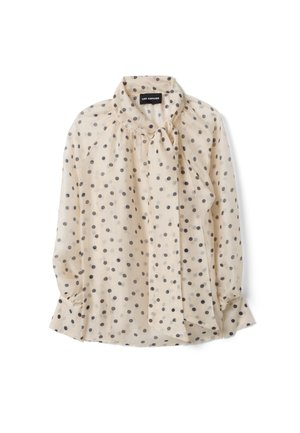 Blusa beige a maniche lunghe con pois neri, collo alto e dettaglio a fiocco annodato sullo scollo.