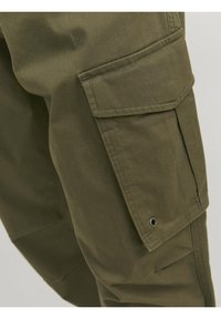 Cargo kalhoty z olivově zelené bavlny, s velkou boční kapsou, šicími detaily a hladkou texturou. Navrženy pro užitečnost a pohodlí.