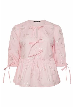 Roze katoenen blouse met driekwart mouwen, voorzien van zilveren strikborduursels, een geraffineerde taille en strikjes bij de hals en mouwmanchetten.