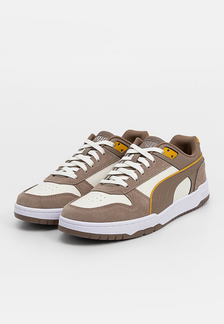 Sneaker marroni e crema con tomaia in suede testurizzato, punta perforata, lacci bianchi e un accento giallo sul lato. Suola in gomma.