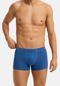 Modré boxerské trenýrky s těsným střihem, vyrobené z měkké, elastické látky. Mají elastický pas a ozdobné švy.