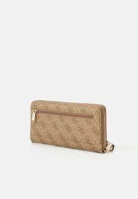 Beige Brieftasche mit Reißverschluss und geprägtem Logomuster. Verfügt über einen dekorativen Reißverschlussanhänger und eine glatte, strukturierte Oberfläche.