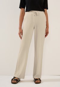 Light beige wide-leg pants with a textured fabric, featuring an elastic waistband with a drawstring, paired with black sandals.