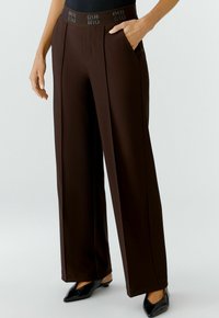 Braune weite Hosen mit einem strukturierten Bund, der Branding trägt. Entworfen mit Seitentaschen und einer glatten Stofftextur.
