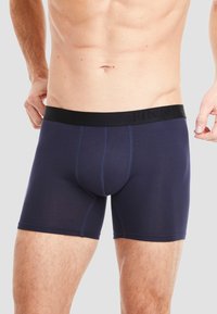 Navy blue boxer brief made of soft fabric with a black elastic waistband featuring embossed "FINN" branding. Seamless construction for comfort.