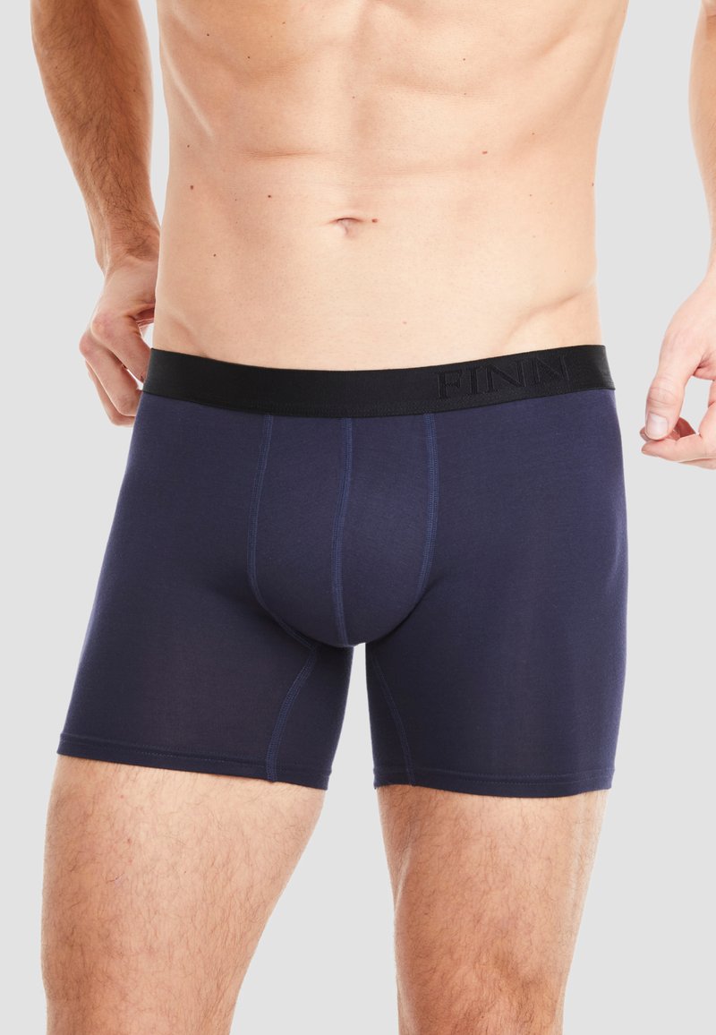 Navy blue boxer brief made of soft fabric with a black elastic waistband featuring embossed "FINN" branding. Seamless construction for comfort.