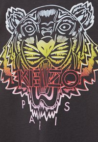 Camiseta negra con un gráfico colorido de un tigre con patrones de pelaje detallados y el texto "KENZO PARIS" debajo en negrita roja y rosa.