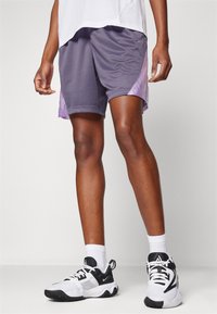 Paarse netstof shorts met een gradientstijl, met een contrasterende lichtere paarse accent aan de linkerkant. Draagt met zwarte en witte sportschoenen.