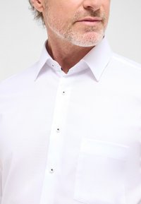 Witte button-up shirt van een textuurstof, met een klassieke kraag en een enkele borstzak. Voorzien van zilveren knopen en een slim fit ontwerp.