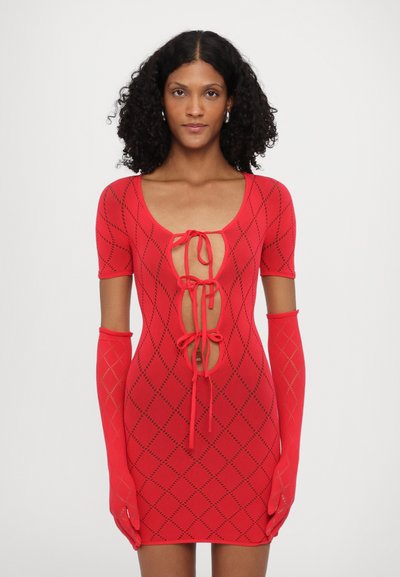 Red knit mini dress with short sleeves, featuring a deep V neckline, diamond patterns, and tie closures at the front and sleeves.