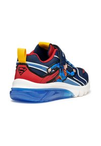 Blauwe sportieve schoen met Superman-afbeelding, rode en gele accenten, bovenwerk van gaas, klittenband en een heldere blauwe rubberen zool.