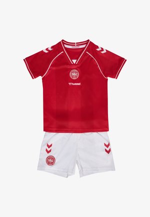 Rød fodboldtrøje med korte ærmer med hvid kant og logo, kombineret med hvide shorts med røde chevrons og matchende logo på venstre ben.