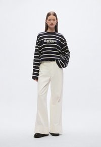 Marineblauw met witte gestreepte trui met lange mouwen en het logo "Barbour EST. 1894", gecombineerd met witte, hoge, wijde broekspijpen.