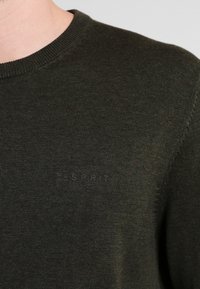 Tmavě olivově zelený pletený svetr s kulatým výstřihem, s jemným vyraženým logem "Esprit" na hrudi a texturovaným povrchem.