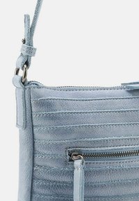 Borsa a tracolla in pelle azzurro chiaro con superficie texturizzata, caratterizzata da cuciture orizzontali, una tasca con zip e una tracolla removibile.