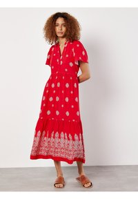 Rotes Kleid mit kurzen Ärmeln, V-Ausschnitt, verziert mit silbernen Blumenmustern und einer gerafften Taille. Der Saum hat eine aufwendige bestickte Bordüre.