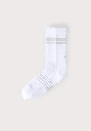 Chaussette blanche mi-mollet avec des rayures gris clair près du dessus et de la voûte plantaire, posée à plat sur un fond pâle.