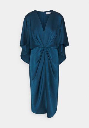 Robe en satin teal avec un décolleté en V profond, des manches flottantes et des détails froncés à la taille, créant une silhouette fluide.