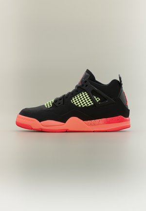 Baskets montantes noires avec mesh jaune fluo et semelle corail vif ainsi que des accents sur un fond clair uni.
