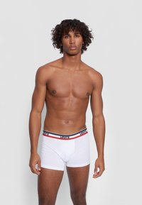 White cotton boxer briefs with a black and red striped waistband featuring "Levi's" logo. Smooth texture, fitted design, and mid-thigh length.