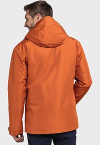 Veste isolante orange avec capuche, manches longues et texture lisse. Design simple sans motifs ni embellissements visibles.